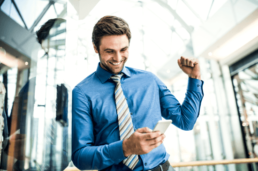a young excited businessman looking at smartphone